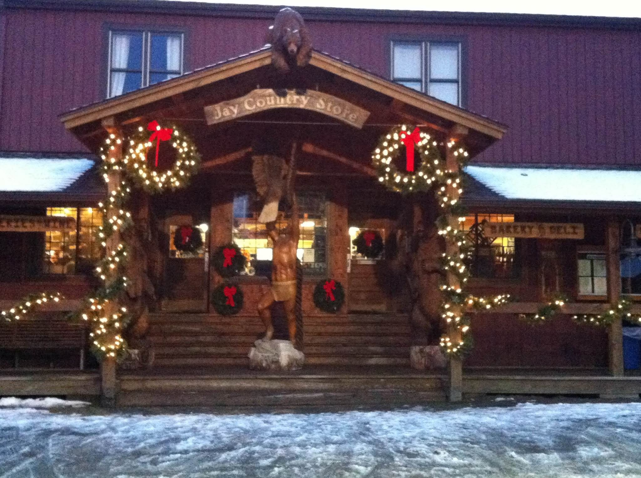 Jay Country Store entrance with its wooden carving, illuminated wreaths, and snow